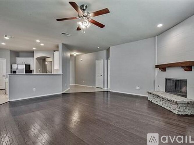 A spacious living room with a fireplace and a ceiling fan.