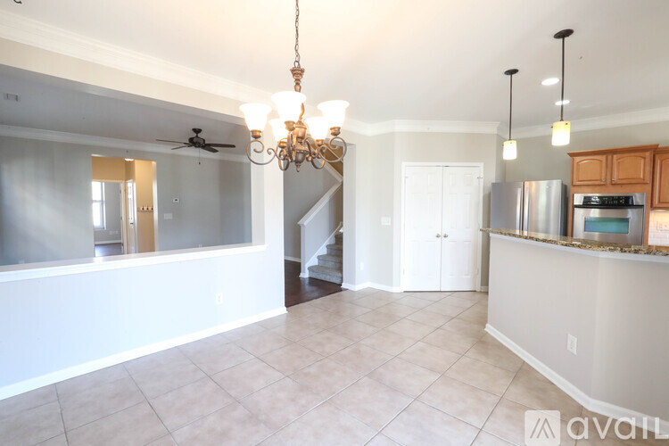 A well-lit kitchen with a chandelier and a refrigerator.