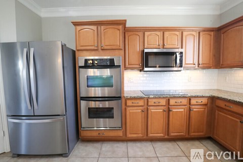 A kitchen with wooden cabinets and a stainless steel refrigerator.