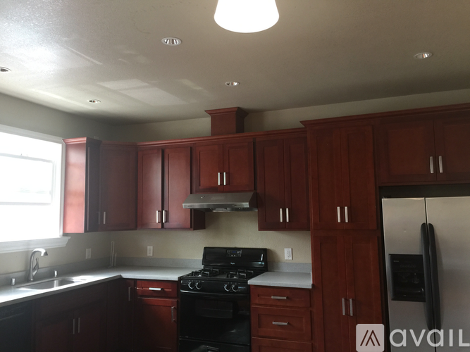 A kitchen with brown cabinets and a black stove top oven.