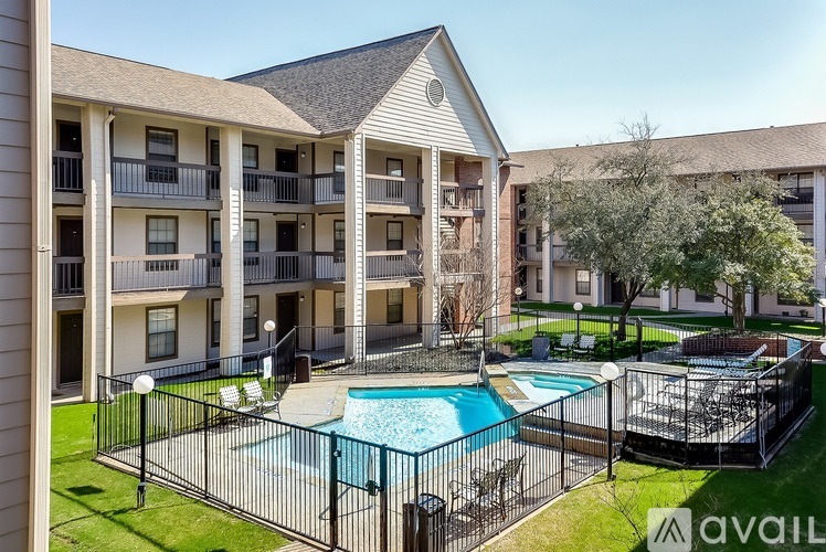 A pool surrounded by a black fence in a grassy area.