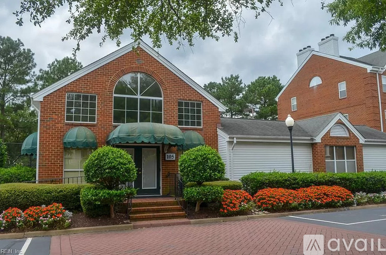 A red brick house with a green awning and a black gate.