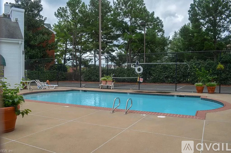 A pool surrounded by trees and a fence with a slide.