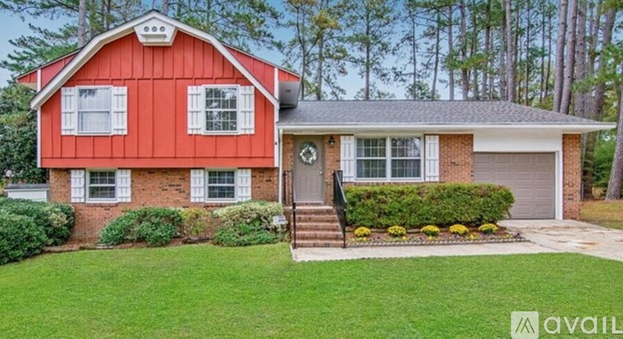 A red house with a white window and a grey garage door.