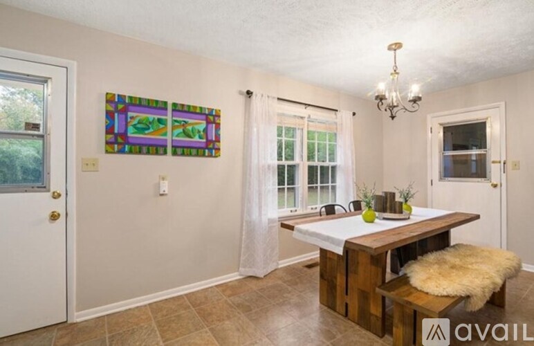 A dining room with a wooden table and bench, a chandelier, and a painting on the wall.
