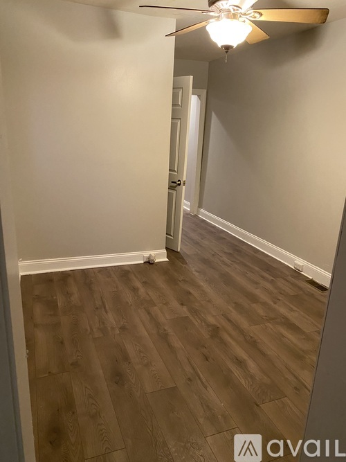 A hallway with wood flooring and a ceiling fan.