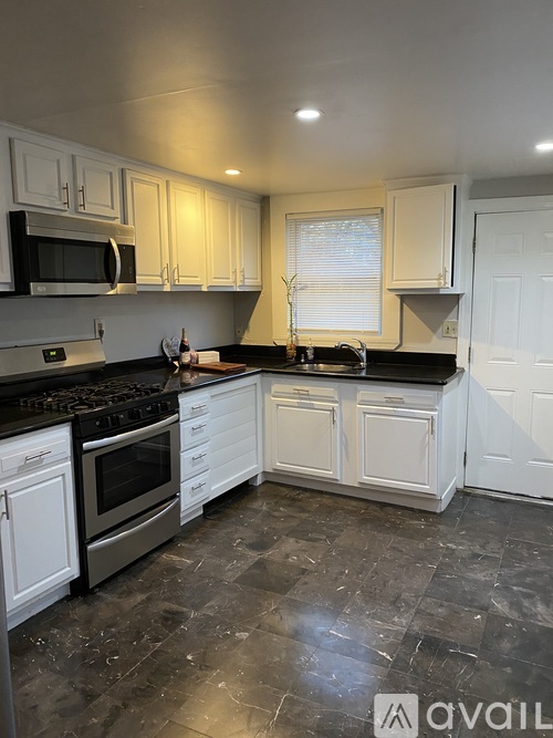 A kitchen with black countertops and white cabinets.