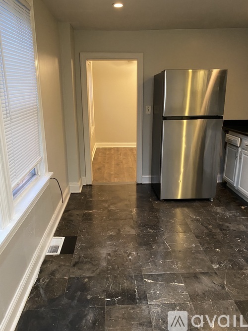A kitchen with a black marble floor and a stainless steel refrigerator.