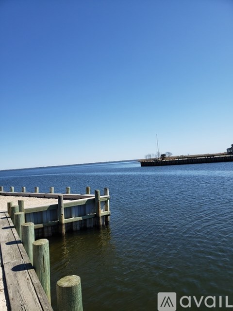 A dock extends into a calm body of water under a clear blue sky.