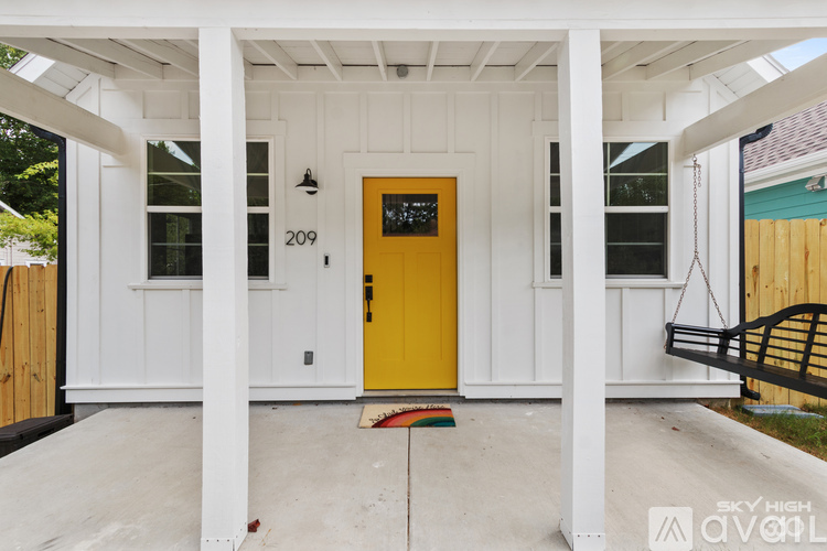 A white house with a yellow door and a bench outside.