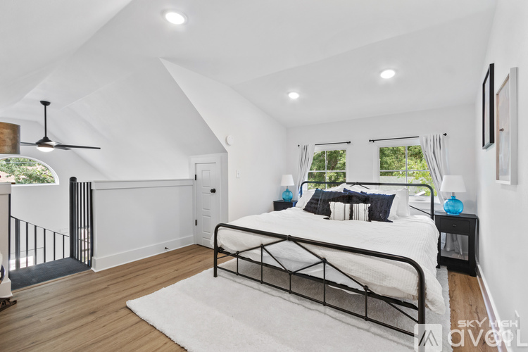 A bedroom with a large bed and a balcony with a railing.