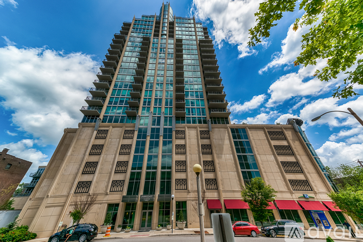 A tall building with a glass facade and a red awning on the ground floor.