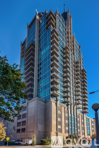 A tall building with many windows and a blue sky in the background.