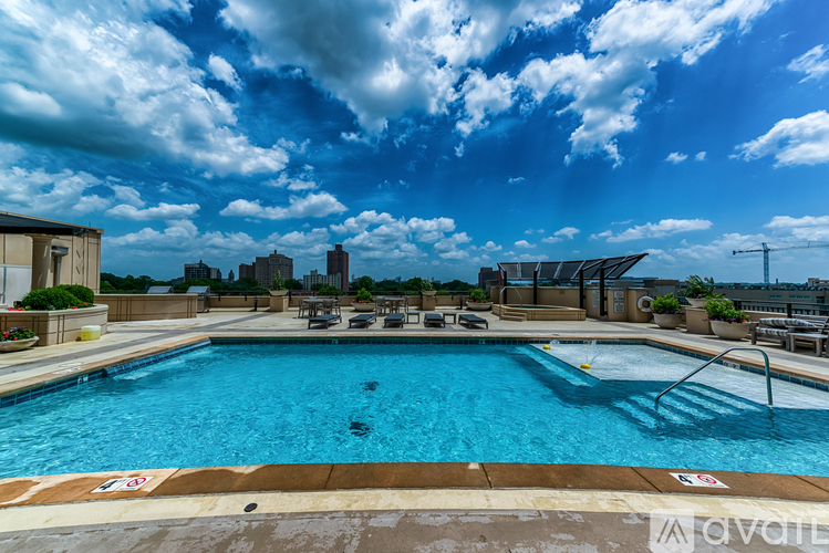 A large swimming pool with a sun shade and a city skyline in the background.