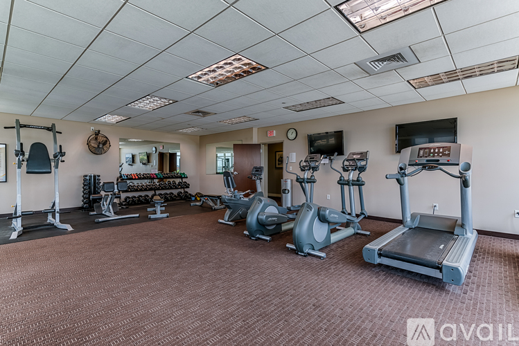 A gym with a variety of equipment including treadmills, weights, and exercise machines.