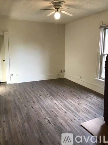A room with a ceiling fan and wooden flooring.