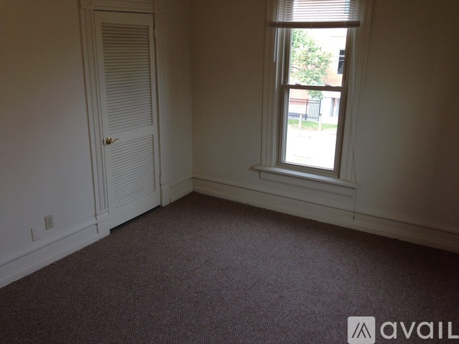 A room with a carpeted floor, a window, and a door.