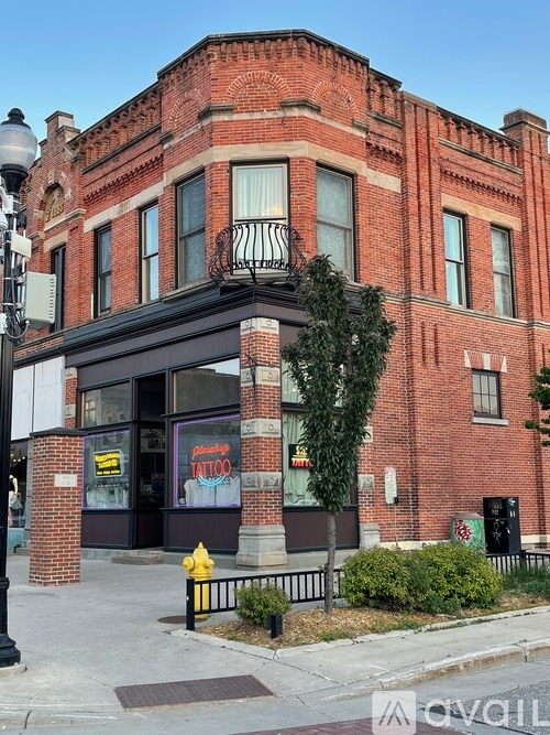 A red brick building with a black awning and a yellow fire hydrant in front.