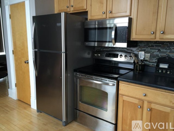 A kitchen with a black countertop and stainless steel appliances.
