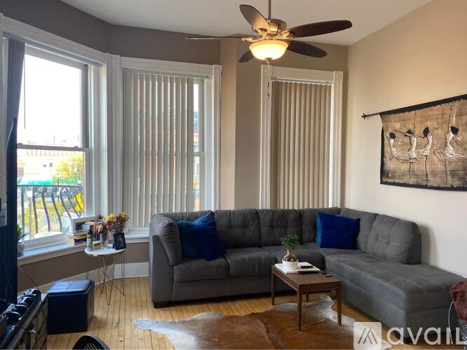 A living room with a grey couch and a ceiling fan.
