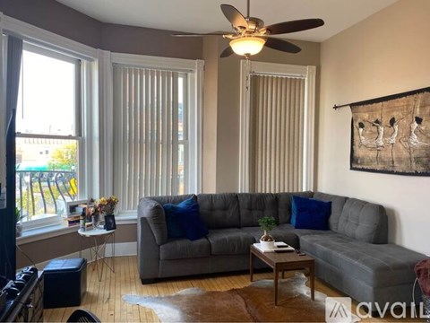 A living room with a grey couch and a ceiling fan.