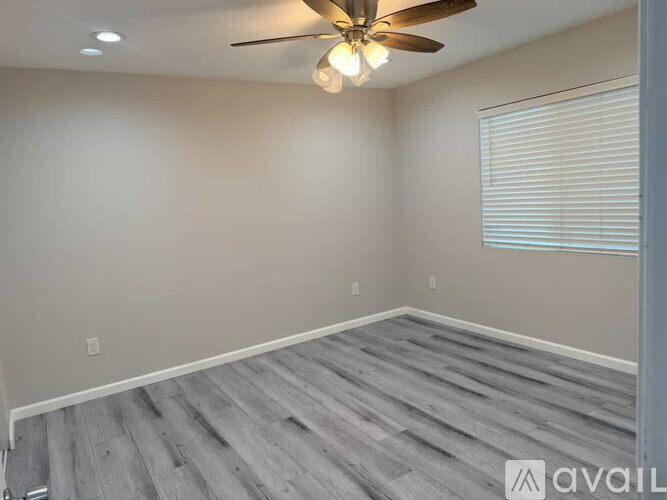 A room with a ceiling fan and wooden flooring.