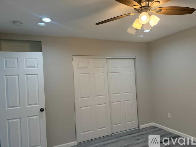 A room with a ceiling fan and two doors.