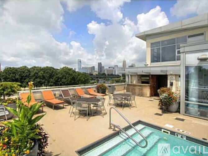 A pool area with chairs and a view of the city skyline.