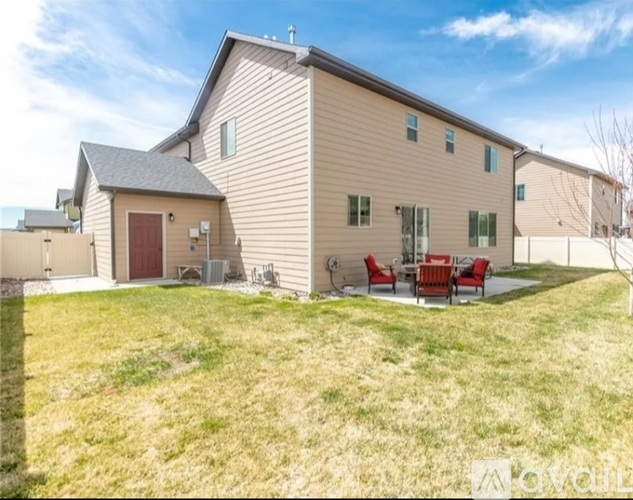 A house with a red door and a patio with red chairs.