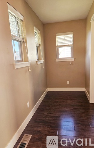 A room with wooden floors and two windows.