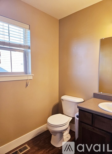 A bathroom with a toilet, sink, and window.