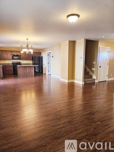 A spacious room with wooden floors and a kitchen area with a refrigerator, microwave, and oven.