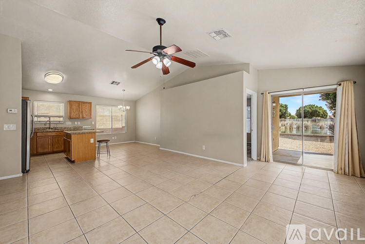 A spacious living room with a ceiling fan and sliding glass doors leading to a backyard.