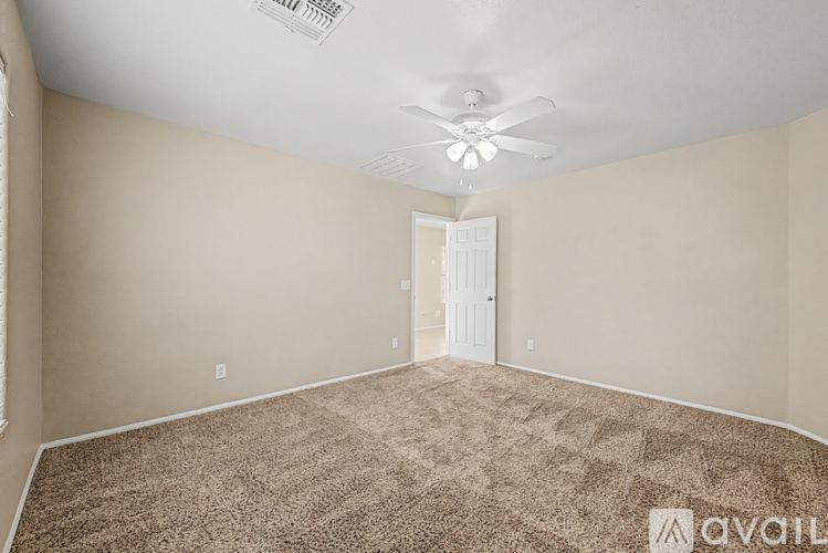 A room with a carpeted floor and a ceiling fan.