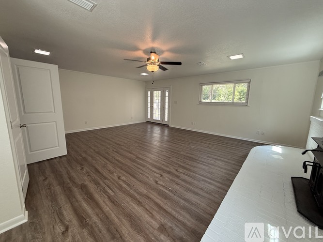 A spacious room with wooden flooring and a ceiling fan.