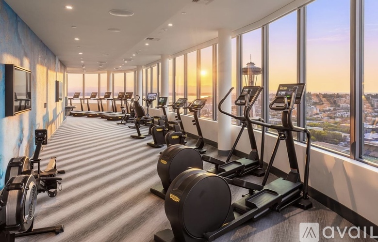 A gym with treadmills, exercise bikes, and a view of the city.