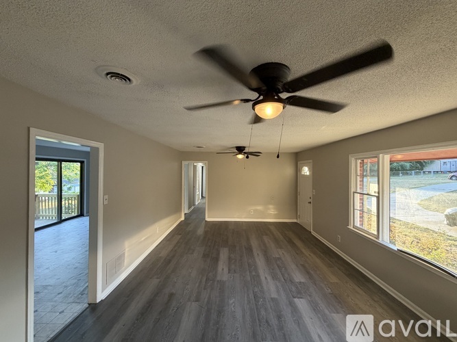 A spacious room with a ceiling fan and hardwood flooring.