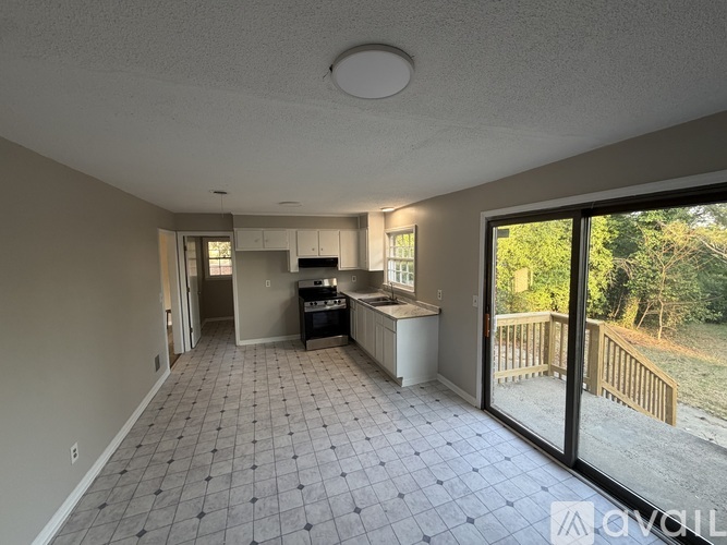 A kitchen area with tile flooring and a view of the backyard through the sliding glass doors.