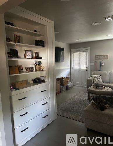 A room with a white chair and a cabinet with drawers and shelves.