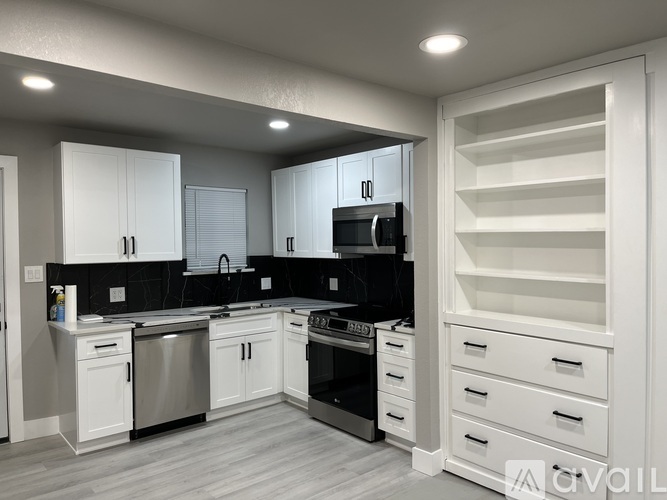 A modern kitchen with white cabinets and black countertops.