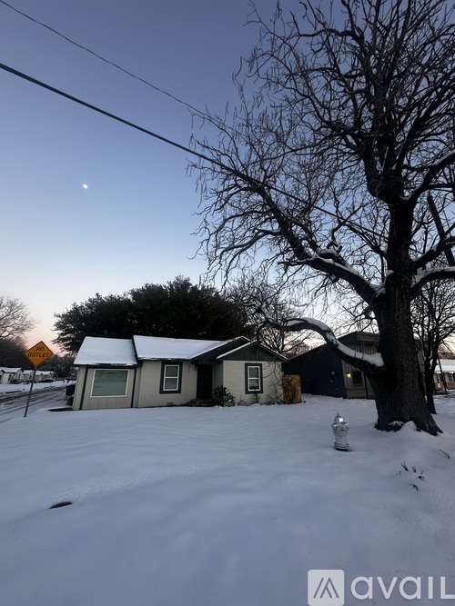A snowy landscape with a tree, a house, and a moon in the sky.