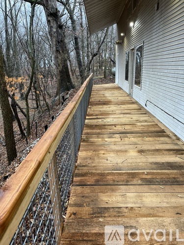 A wooden deck with a metal railing and a house in the background.