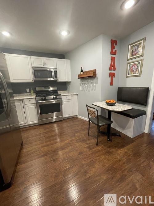 A kitchen with a wooden floor and a dining table with two chairs.