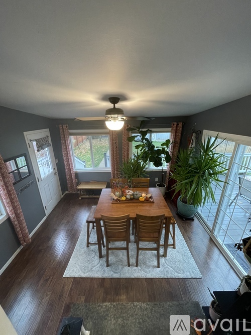 A dining room with a table set for four and a ceiling fan.