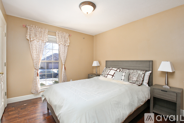 A bedroom with a large bed and a window with curtains.