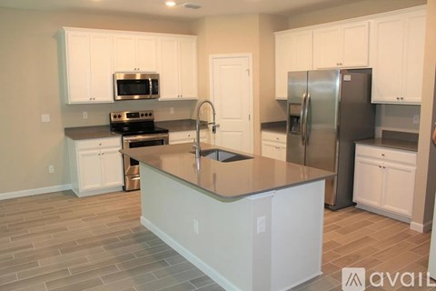 A kitchen with white cabinets and a stainless steel refrigerator.