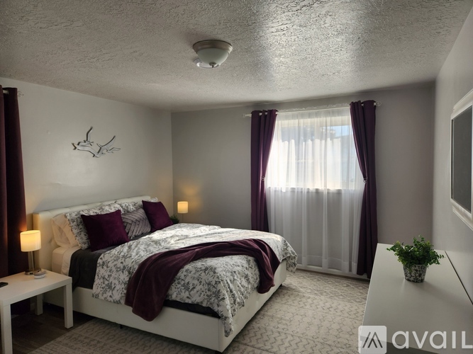 A bedroom with a large bed and a window with curtains.