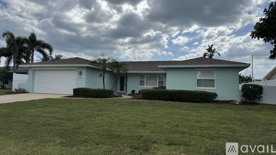 A house with a lawn in front and a cloudy sky above.