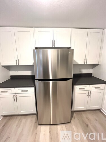 A kitchen with a stainless steel refrigerator and white cabinets.