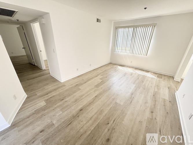 A spacious room with wooden flooring and white walls.